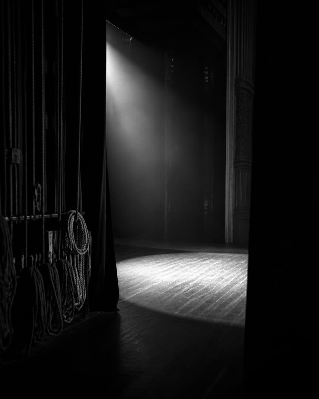 A single spotlight on an empty stage seen from the wings